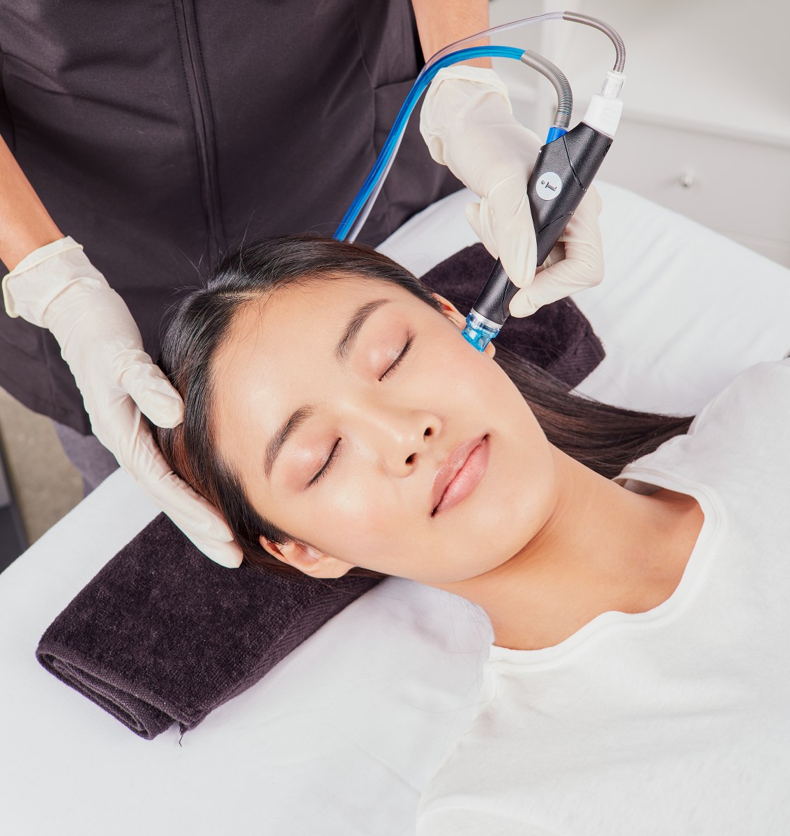 doctor applying a hydrafacial treatment to the cheek of a woman's face.